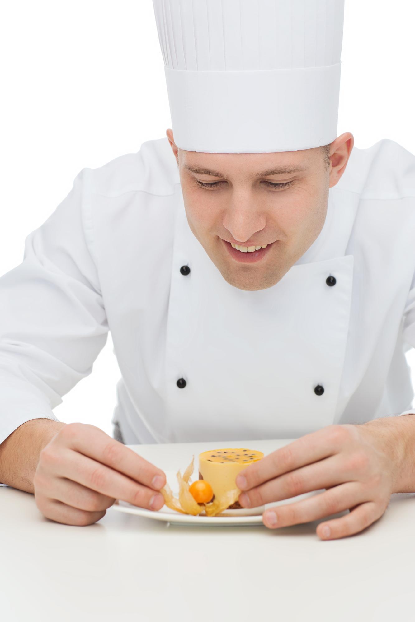 Chef arranging plated dish in soft kitchen light